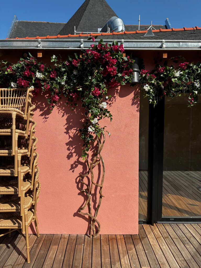 Bougainvillier artificiel fleuri installé sur la façade de la terrasse du restaurant Bambino à Angers, avec des lianes en bois naturel descendant le long du mur.